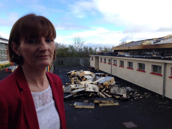 Holy Child principal Orla McDonnell with the damage to the school behind her caused by arsonists