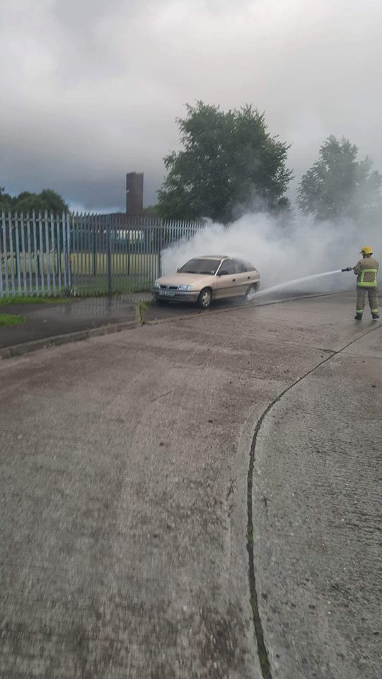 Fire crew member putting out burning car on Carnhill Road