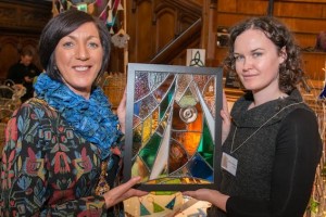 Mayor Councillor Brenda Stevenson with Theresa Coyle from Alpha Stained Glass and a panel showing the Guildhall and Peace Bridge.