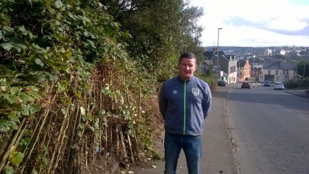 Cllr Colly Kelly on the Newr Road with the overgrown trees/bushes cut back